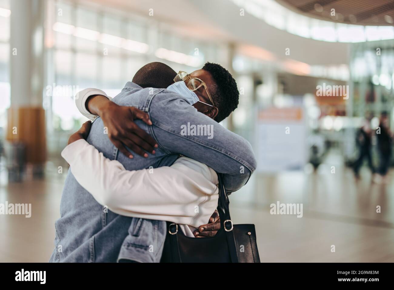 Ein Touristenpaar umarmte Auf Wiedersehen am Abflugsteig des Flughafens. Frau wird von ihrem Mann am Flughafen auf Wiedersehen umarmt. Stockfoto