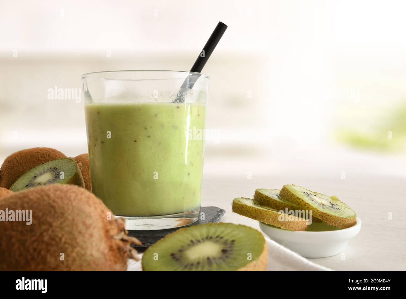 Glas Kiwi-Getränk und Behälter schneiden Obst auf der Küchenbank aus nächster Nähe. Vorderansicht. Stockfoto