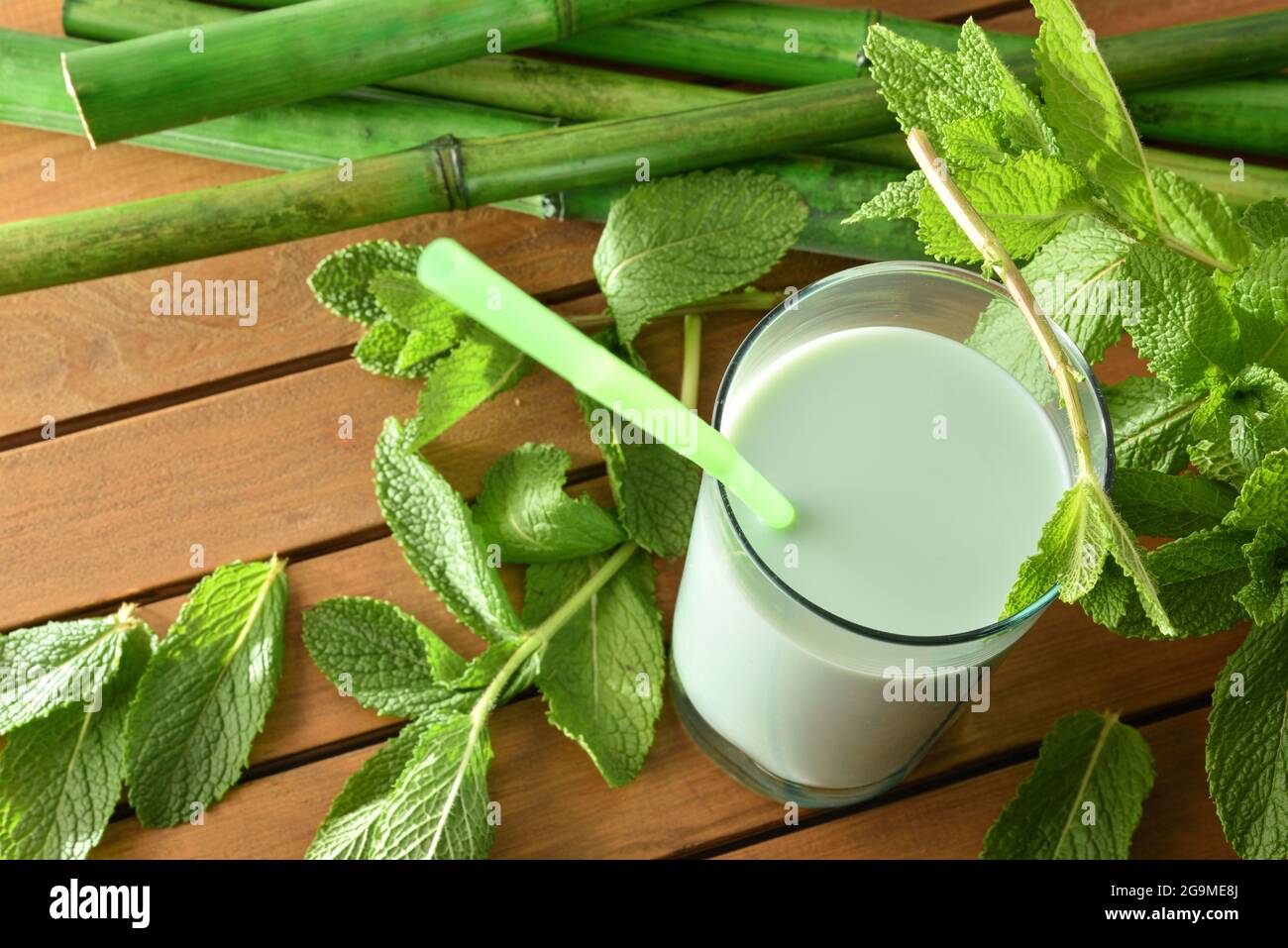 Milchshake mit Minze auf Holztisch und Minzblättern. Blick auf den Fahrstuhl. Stockfoto