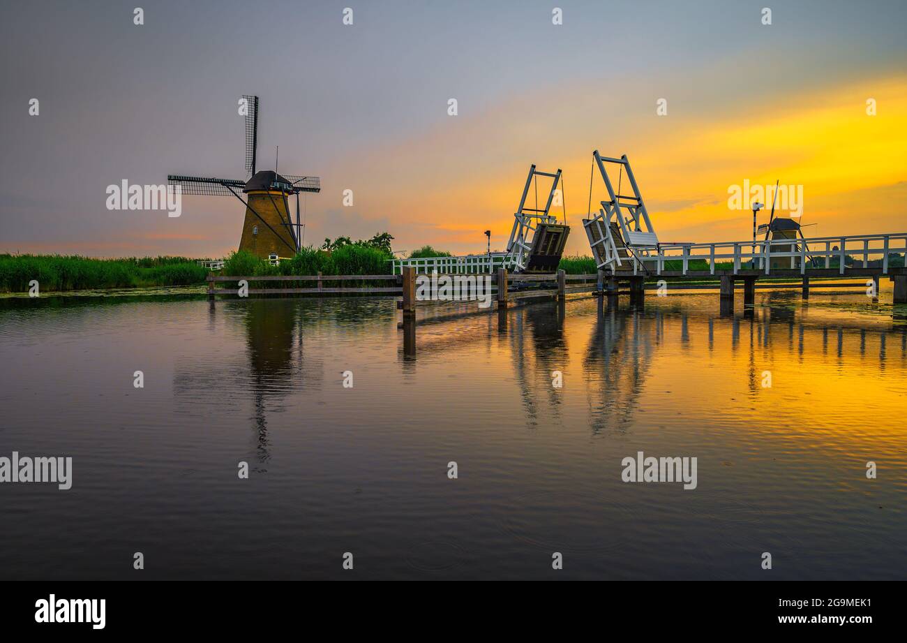 Sonnenuntergang über einer historischen Zugbrücke und alten Windmühlen in Kinderdijk, Niederlande Stockfoto