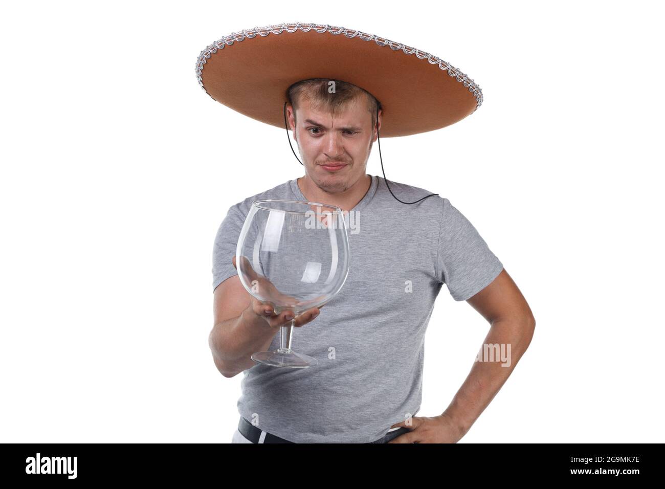 Bild eines jungen Mannes in Sombrero, der großes Glas für Alkohol hält Stockfoto