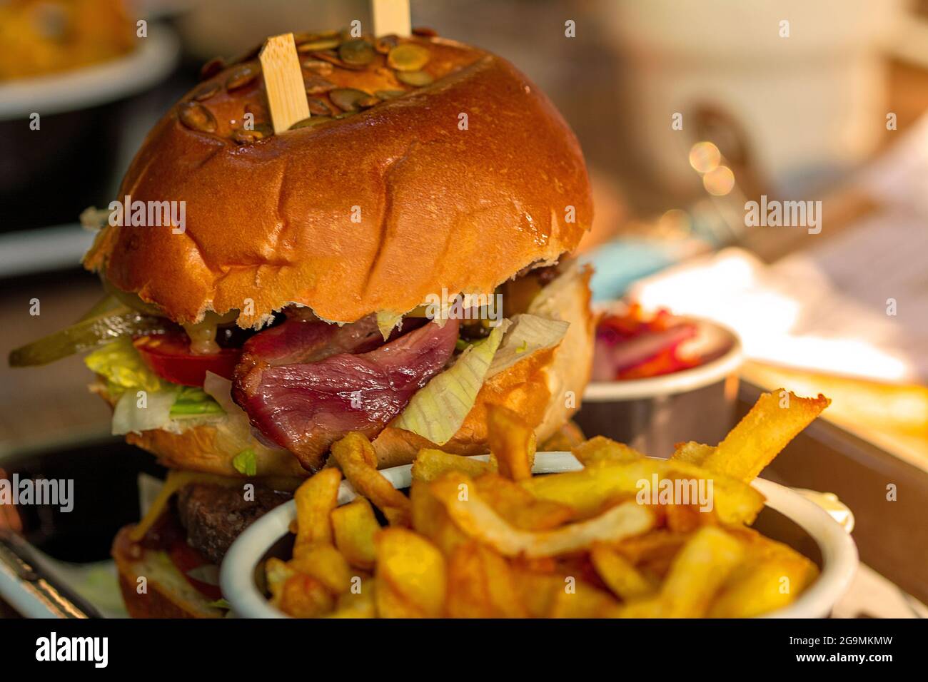 Nahaufnahme eines Burgers in einem Restaurant mit Zwiebelringen, Käse und Gemüse Stockfoto