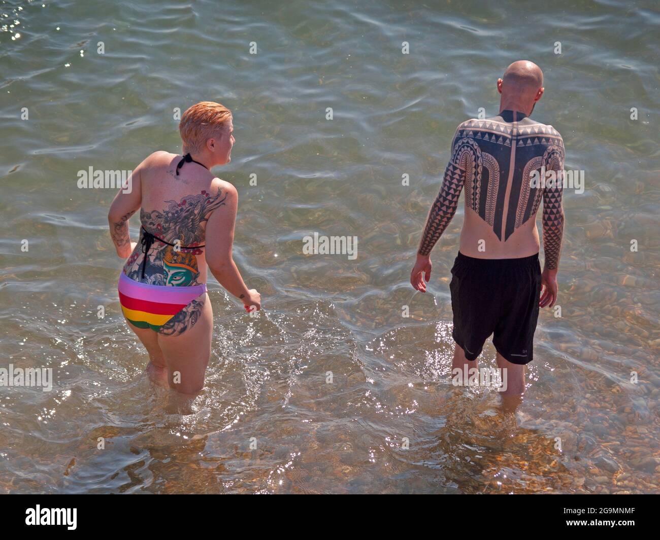 Ein tätowierte Paar kommt in Brighton ins Meer Stockfoto
