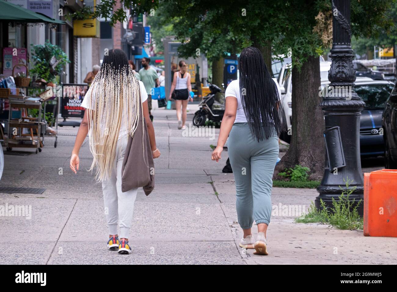 Zwei Frauen mit sehr langen Haarverlängerung gehen auf der Steinway Street in Astoria, Queens, New York, Stockfoto