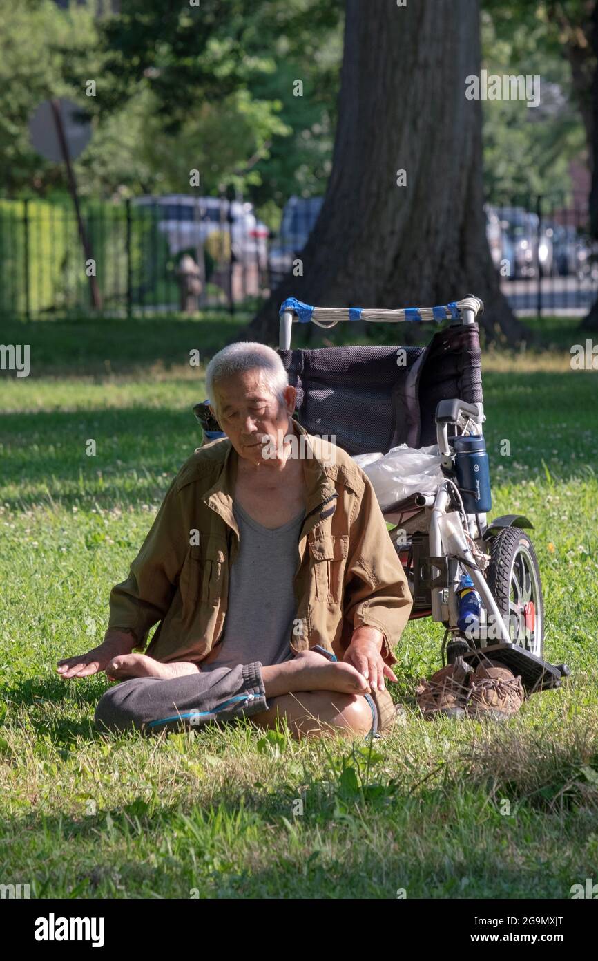 Ein 86-jähriger Mann macht in der Nähe eines Baumes langsam laufende Falun gong-Übungen. In Queens, New York, ein sehr vielfältiger Ort. Stockfoto