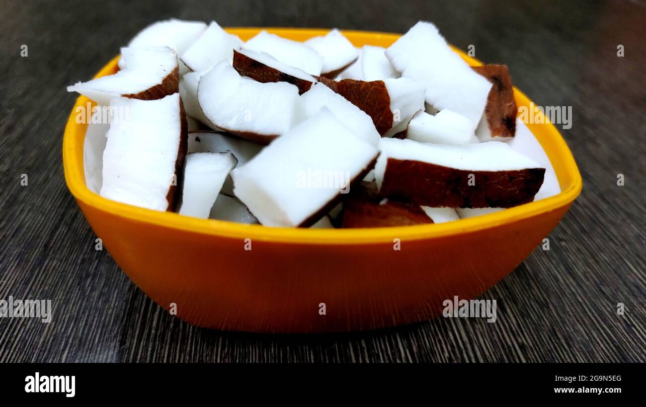 Frische Kokosnussstücke in einer Schüssel auf dunklem Hintergrund mit Kopierraum Stockfoto