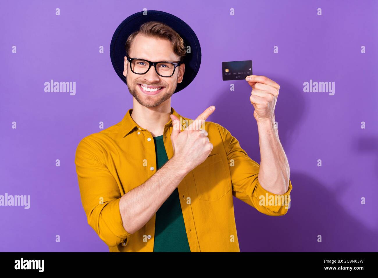 Foto von jungen Kerl glücklich positive Lächeln zeigen Finger Kreditkarte empfehlen Bankzahlung isoliert über violette Farbe Hintergrund Stockfoto