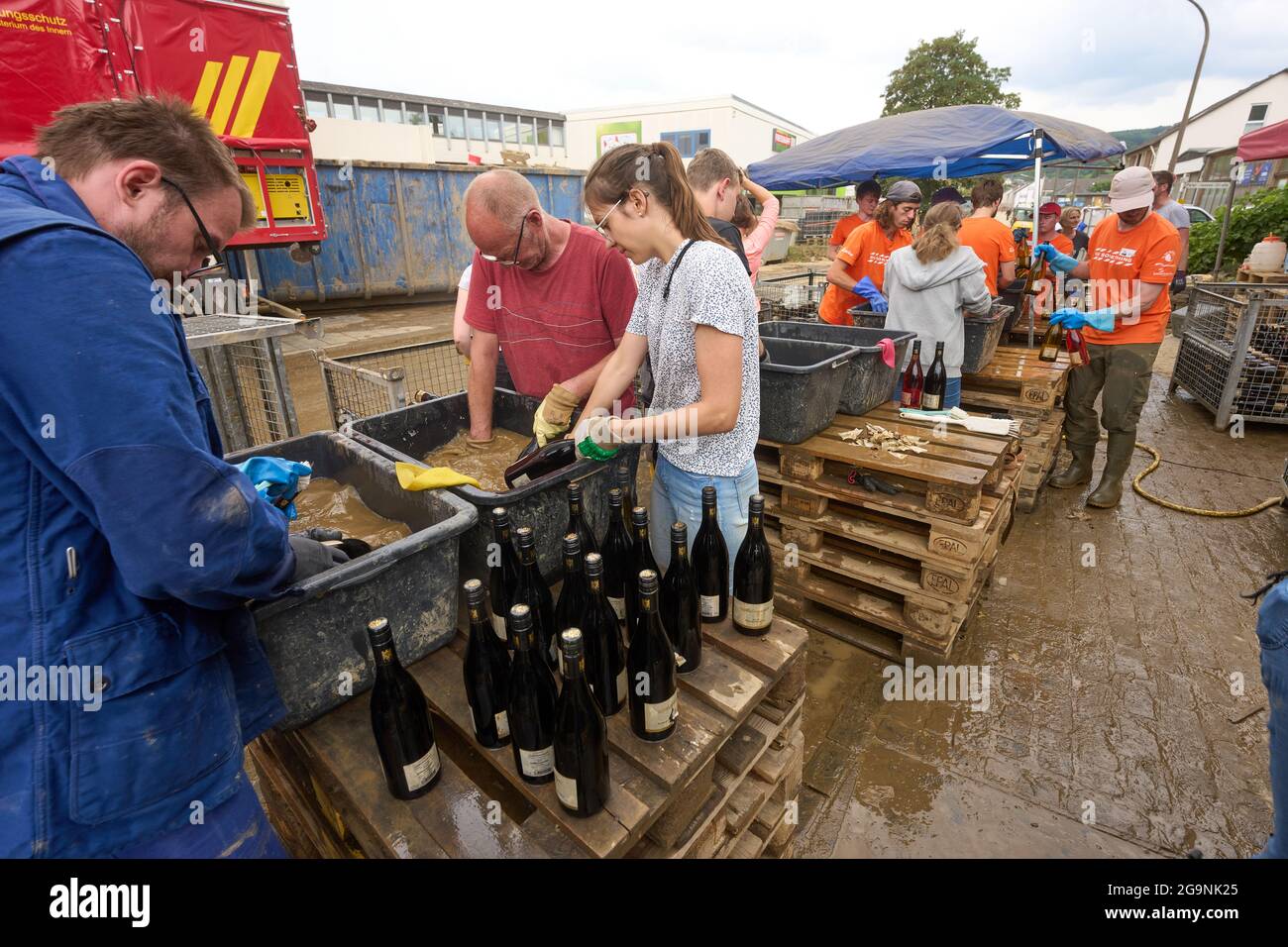 Ahrweiler, Deutschland. Juli 2021. Freiwillige sind in der Adeneuer-Weinkellerei damit beschäftigt, die von der Flut mit Schlamm bedeckten Flaschen zu reinigen. Im Ahrtal, das durch die Überschwemmungen stark verwüstet wurde, werden die Sanierungsarbeiten unvermindert fortgesetzt. Quelle: Thomas Frey/dpa/Alamy Live News Stockfoto