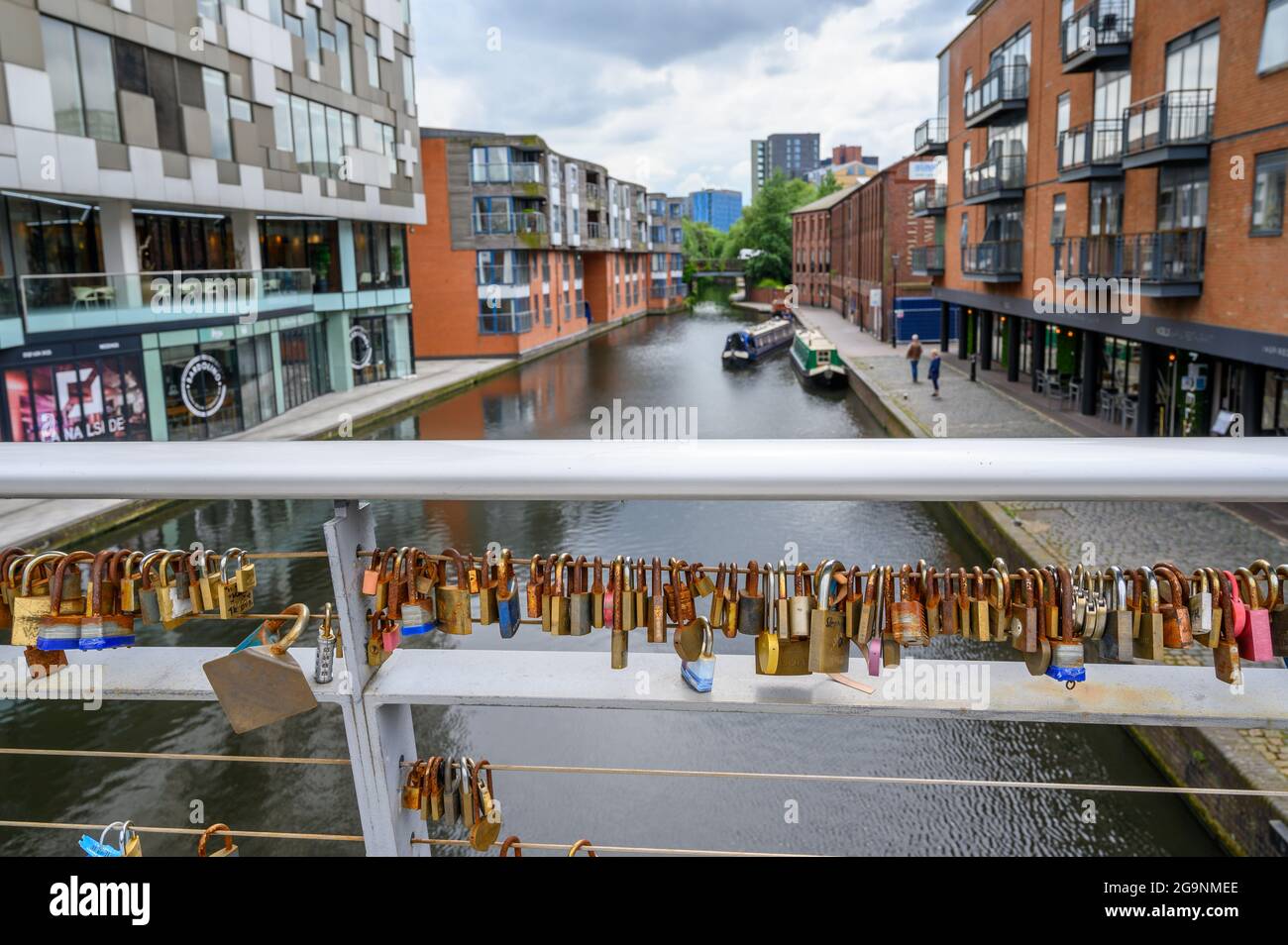 Vorhängeschlösser, die an Geländern auf der Love Lock Bridge über den Birmingham Canal Old Line von The Cube und der Mailbox in Birmingham, England, verschlossen sind. Stockfoto