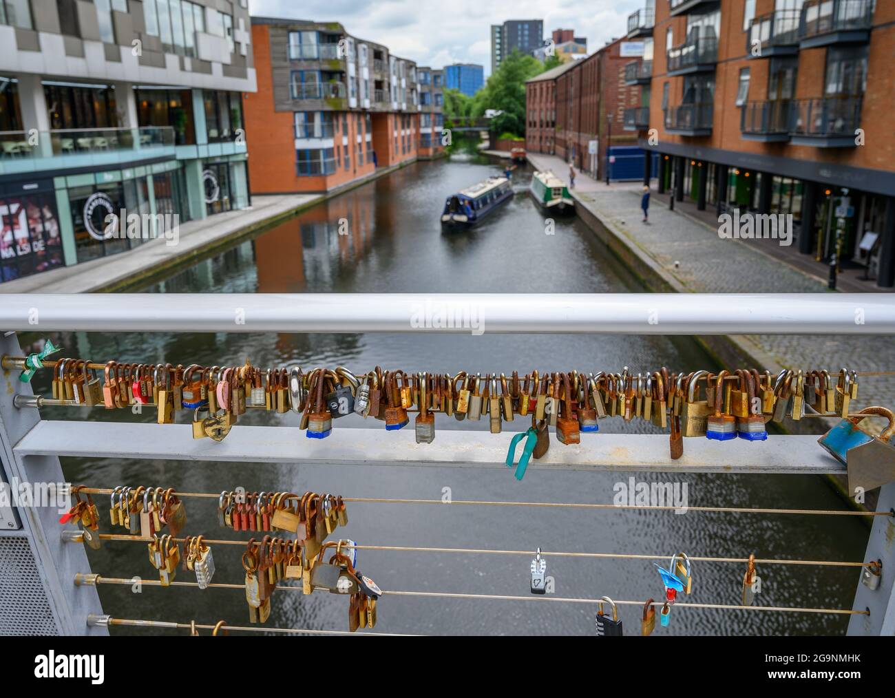 Vorhängeschlösser, die an Geländern auf der Love Lock Bridge über den Birmingham Canal Old Line von The Cube und der Mailbox in Birmingham, England, verschlossen sind. Stockfoto