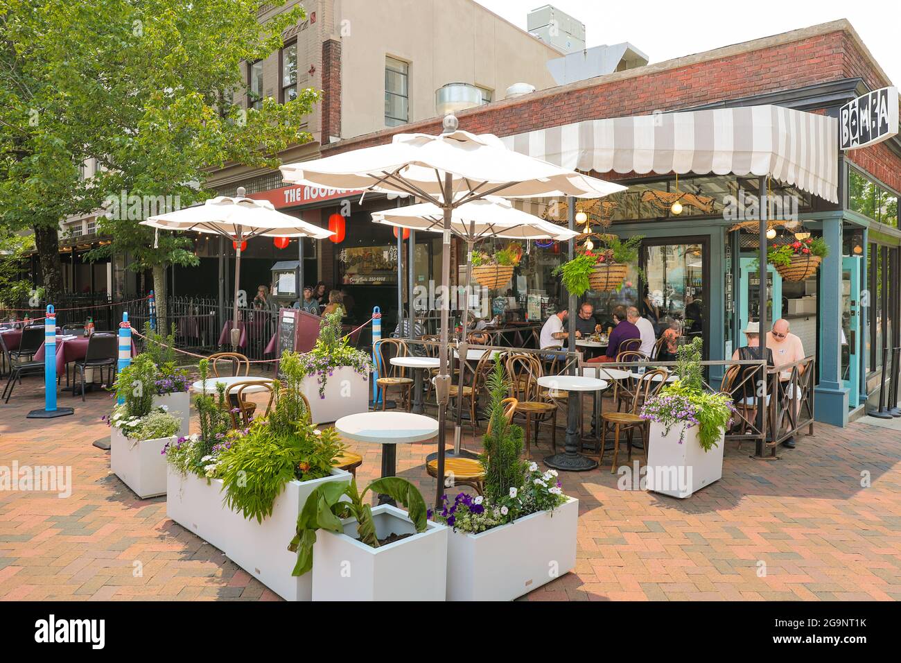 ASHEVILLE, NC, USA-22 JULY 2021: Der Noodle Shop auf dem Pack Square zur Mittagszeit an einem warmen Sommertag, der Tische, Mäzene und Pflanzer im Freien zeigt. Stockfoto