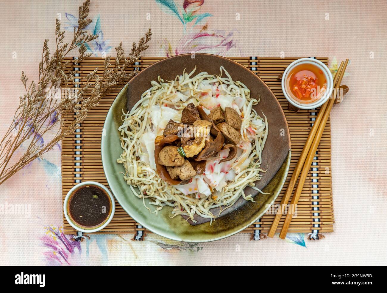 Geschmortes Schweinefleisch, Tofu, knackiger Tintenfisch in süßer Sojasauce, serviert auf chinesischen gedämpften Reisnudeln und Bohnensprossen in Keramikplatte, serviert mit eingelegter Chili. A Stockfoto