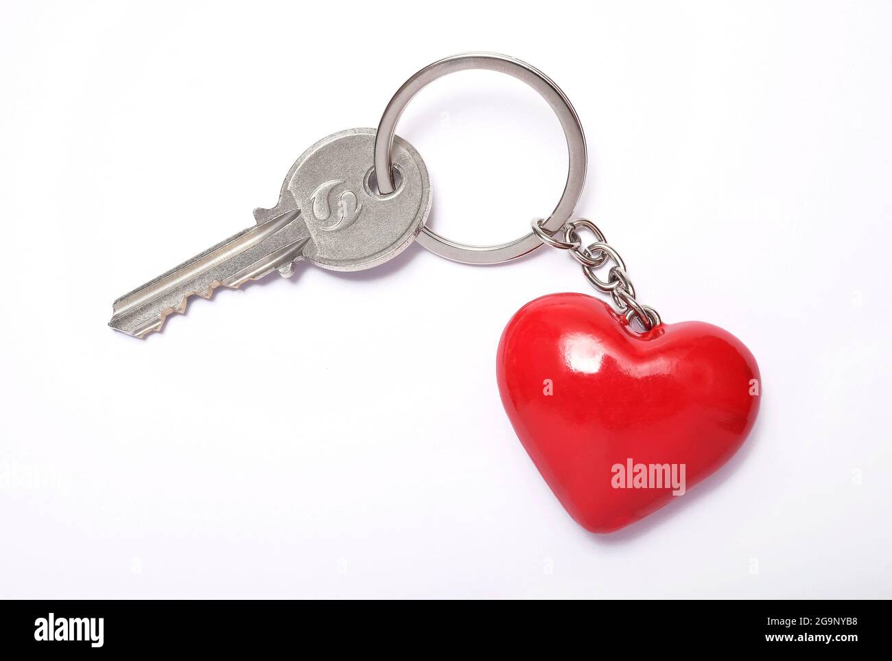 Hausschlüssel und roter herzförmiger Schlüsselanhänger auf weißem Hintergrund Stockfoto