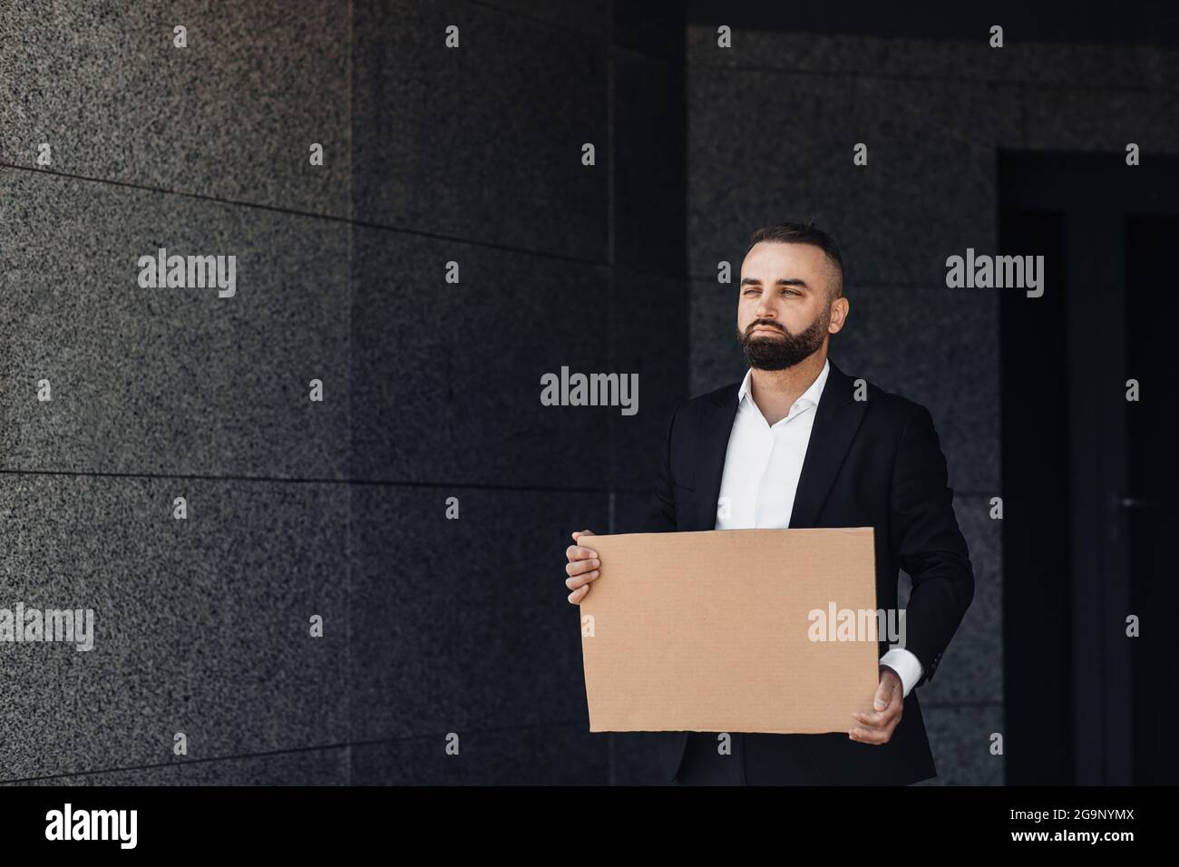 Geschäftsmann zeigt leeres Pappschild, protestiert allein gegen die Sperrung auf der Straße, freien Platz Stockfoto