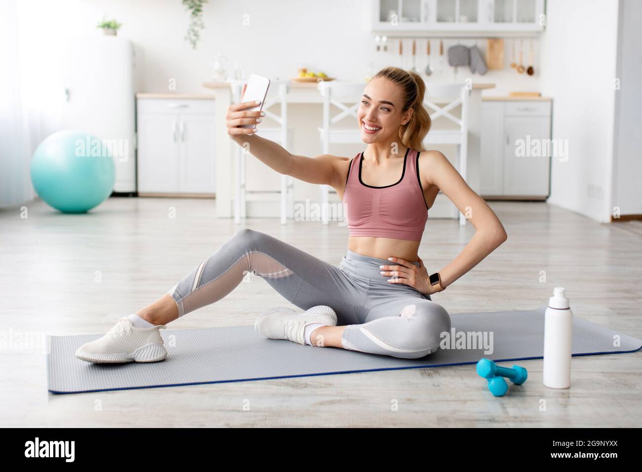 Fitness Model Blogger macht Foto für soziale Netzwerke, modernes Gerät für Arbeit und Training zu Hause Stockfoto