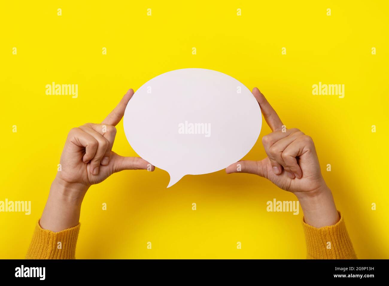Sprechblase Sprechsymbol in Händen über gelbem Hintergrund, Layout für Ihren Text über weißem, rundem Raum Stockfoto