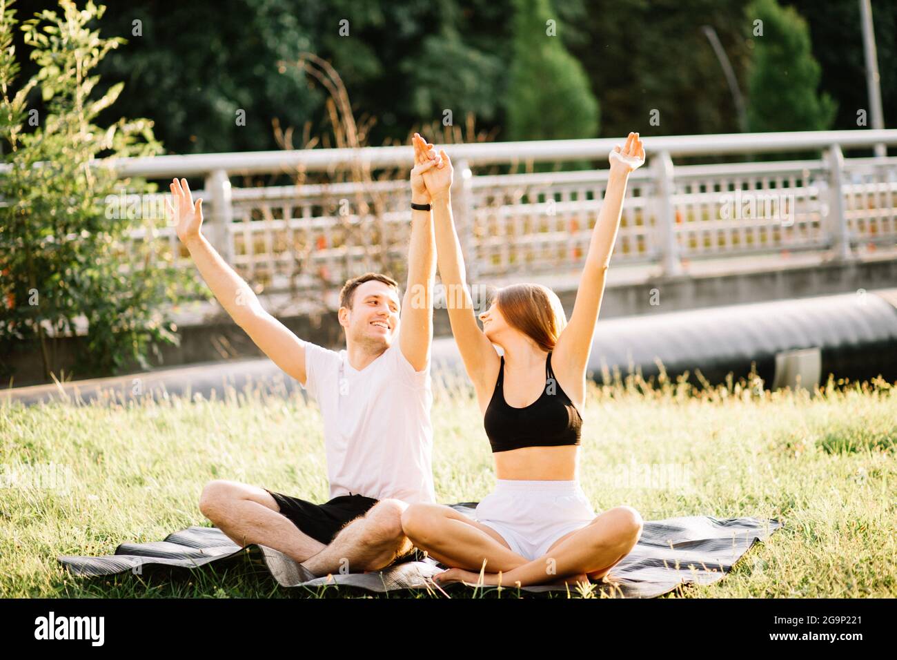 Junges Paar, Mann und Frau beim Sport, Yoga auf dem Stadtgarten, Sommerabend-Zweisamkeit Stockfoto