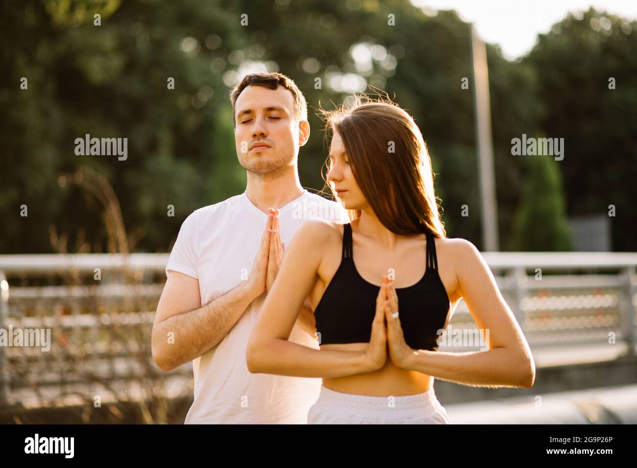 Junge Paar Mann und Frau meditieren im Stehen, Yoga auf dem Stadtgarten, Sommerabend, Lifestyle Stockfoto