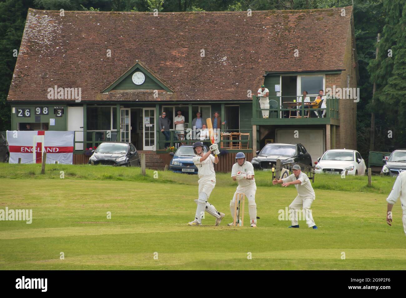 Eine traditionelle englische Sommerlandschaft - Cricket auf einem Dorfgrün - hier in Ockley, Surrey, Großbritannien Stockfoto