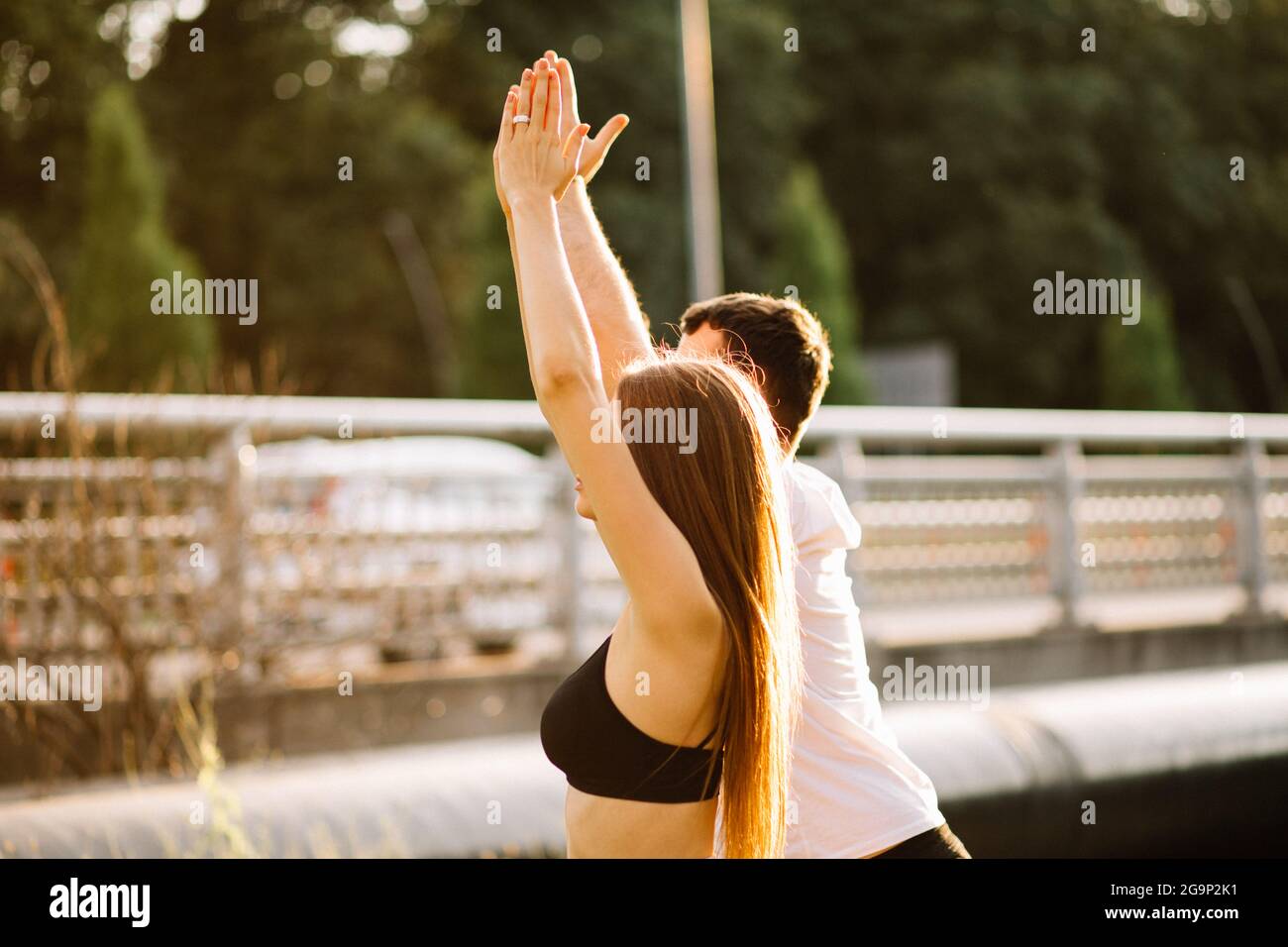 Körperteil Junges Paar von Mann und Frau, die Sport treiben, Yoga auf Stadtrasen, Sommerabend, sich gemeinsam bei Sonnenuntergang ausdehnen, Stadtsport Stockfoto