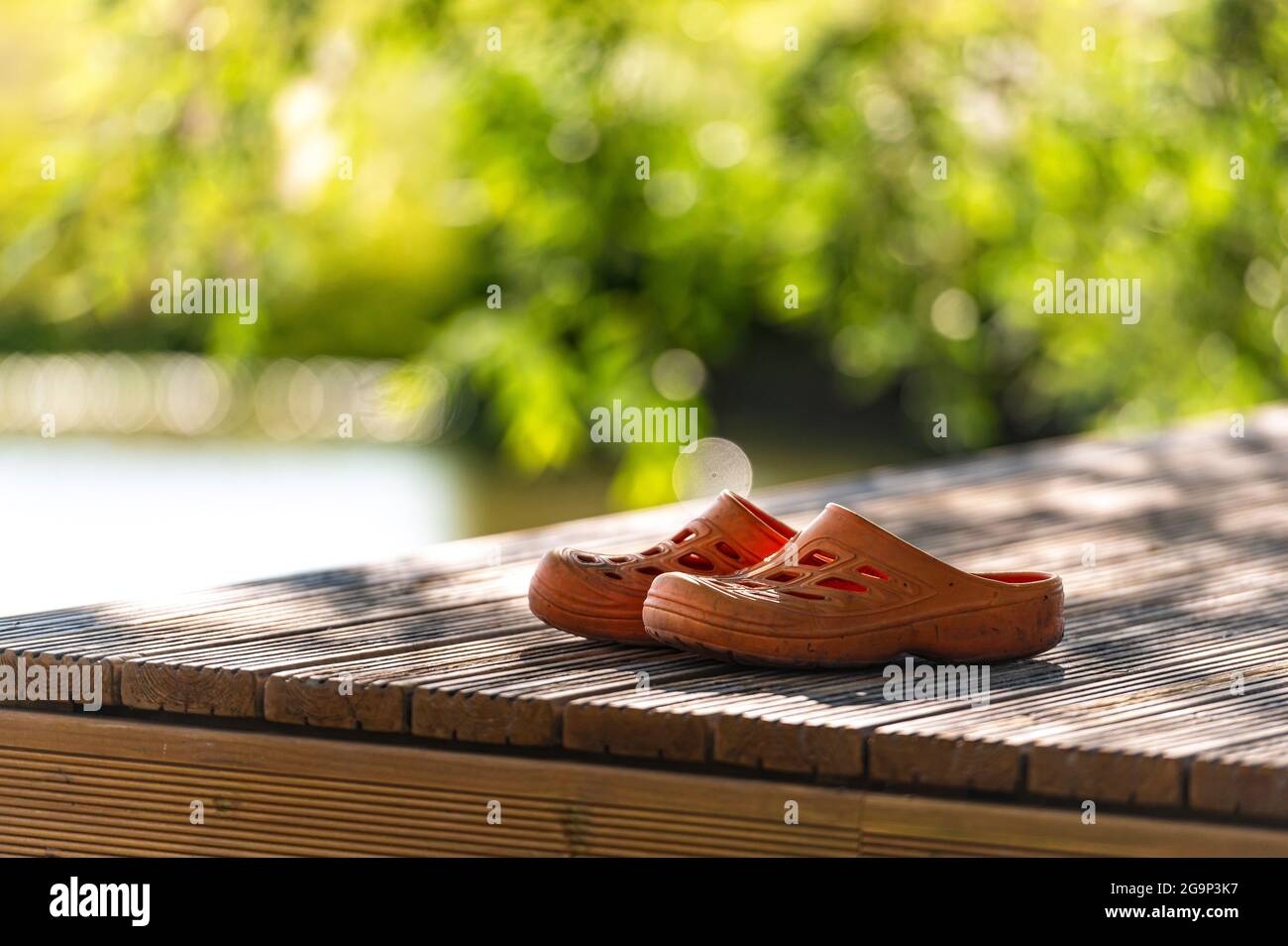 Ein Paar orangefarbene Gummiklobs auf dem Pier am See, Nahaufnahme Stockfoto