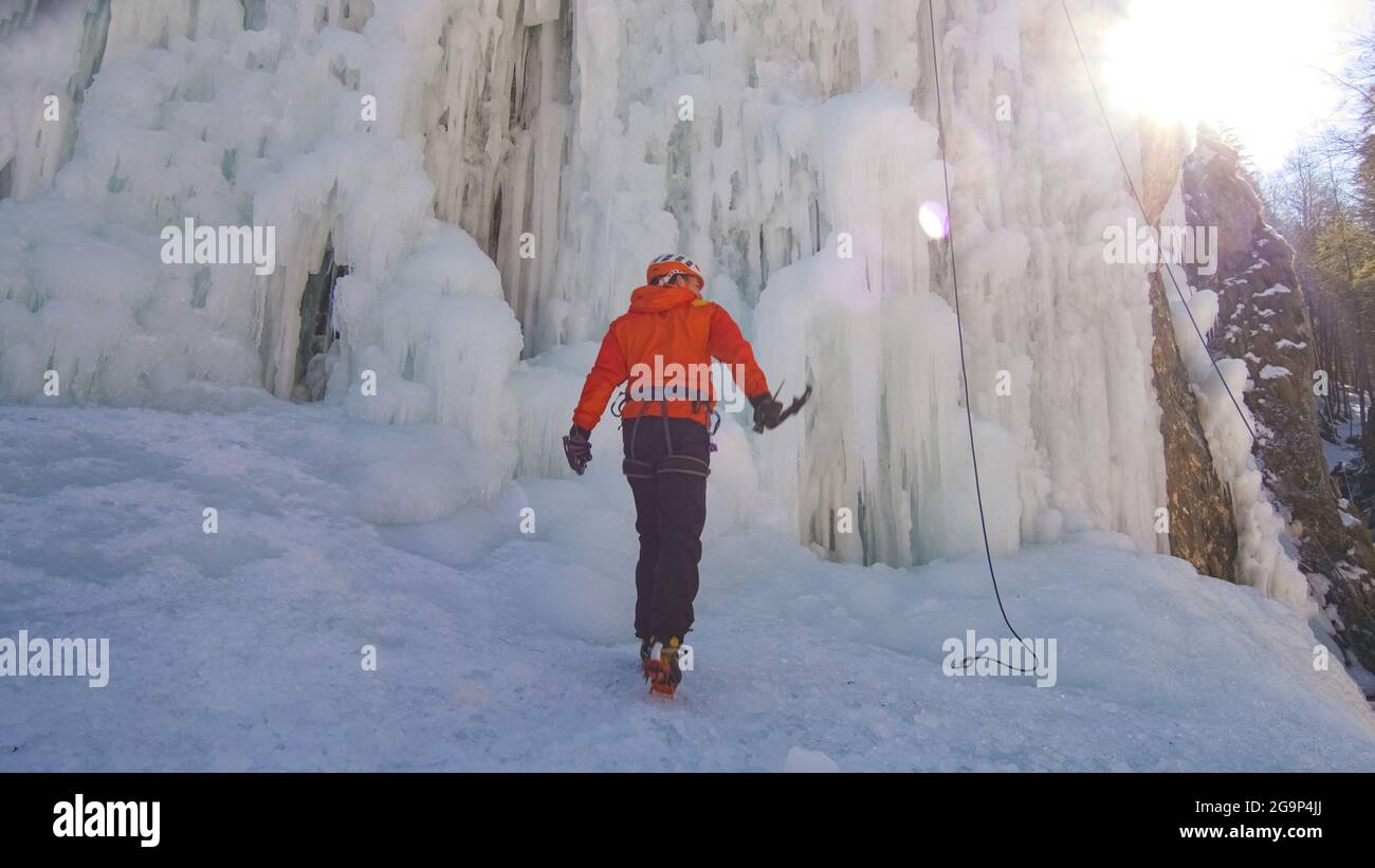 Nahaufnahme eines männlichen kaukasischen Eiskletterers, der ein Seil an sein Geschirr bindet und sich auf einen Aufstieg vorbereitet Stockfoto