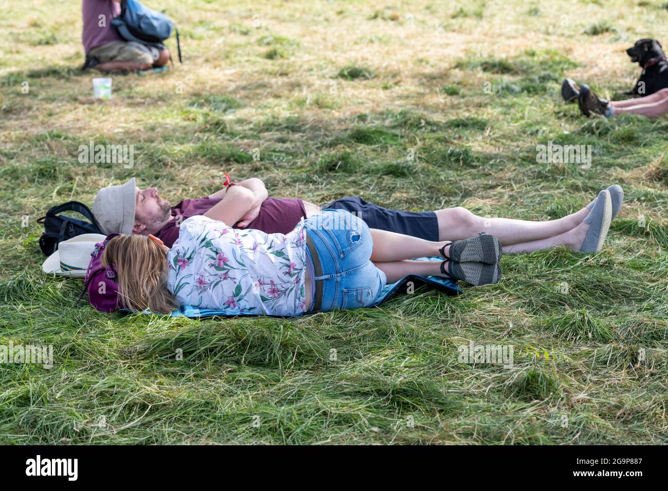 Ein Paar liegt auf dem Rasen und liest ein Buch beim Standon Calling Music Festival 2021 Hertfordshire UK Stockfoto