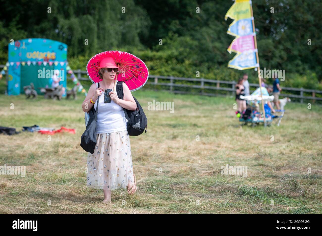 Eine Frau mit rotem Regenschirm und Hut beim Standon Calling Music Festival 2021 Hertfordshire UK Stockfoto