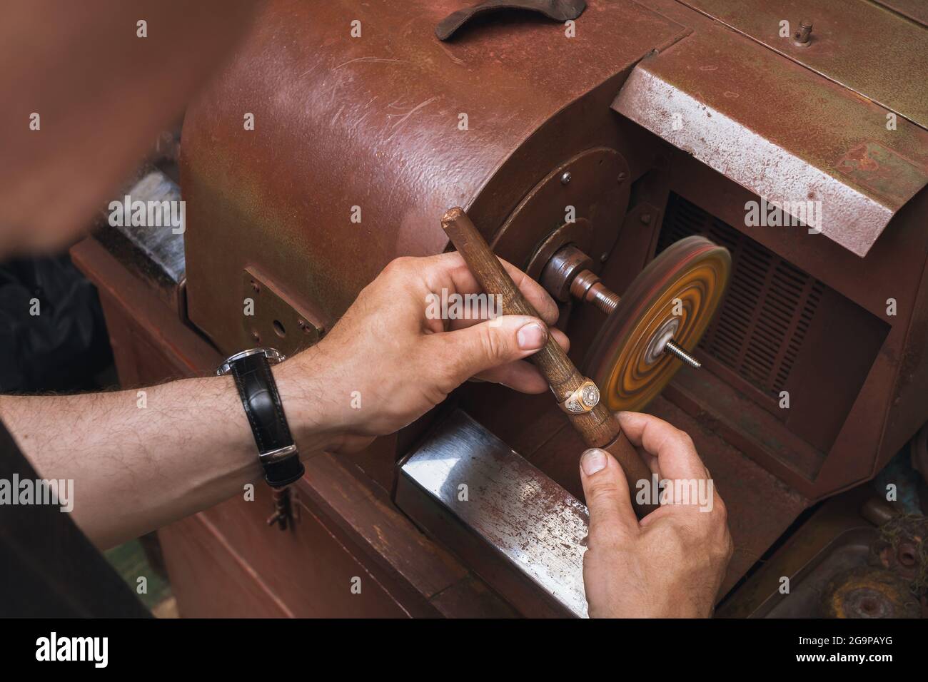 Ein Juwelier poliert einen Goldring an einer Maschine in einer Werkstatt, ein Arbeitsprozess Stockfoto