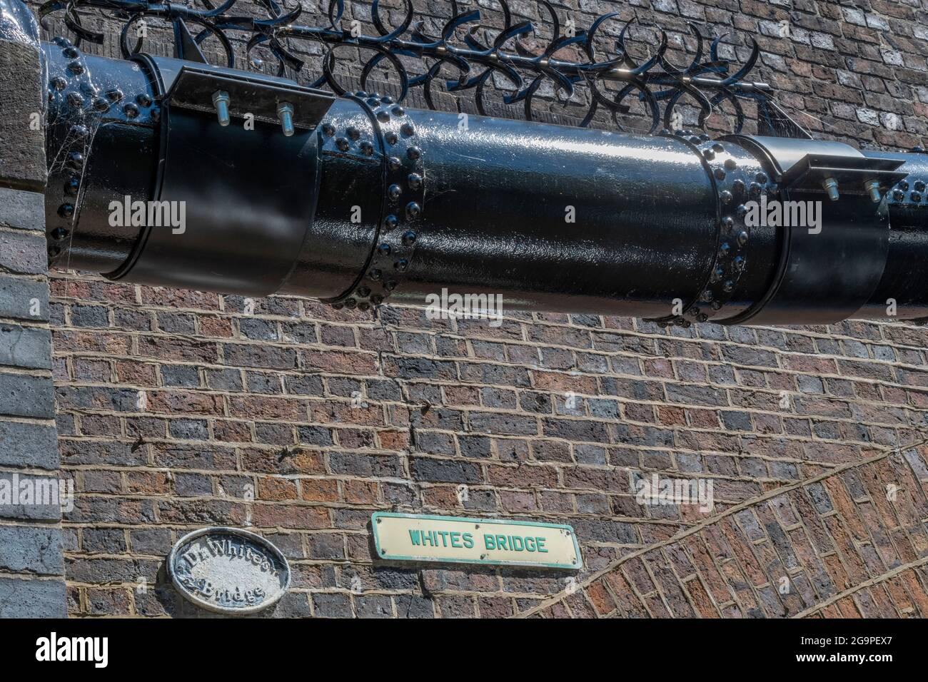 Industrielle rote Backsteinbrücke über den bridgewater-Kanal im Verkauf Greater manchester mit einem Service-Kraftstoff- oder Energiedienstleitung mit einem Anti-Climb. Stockfoto