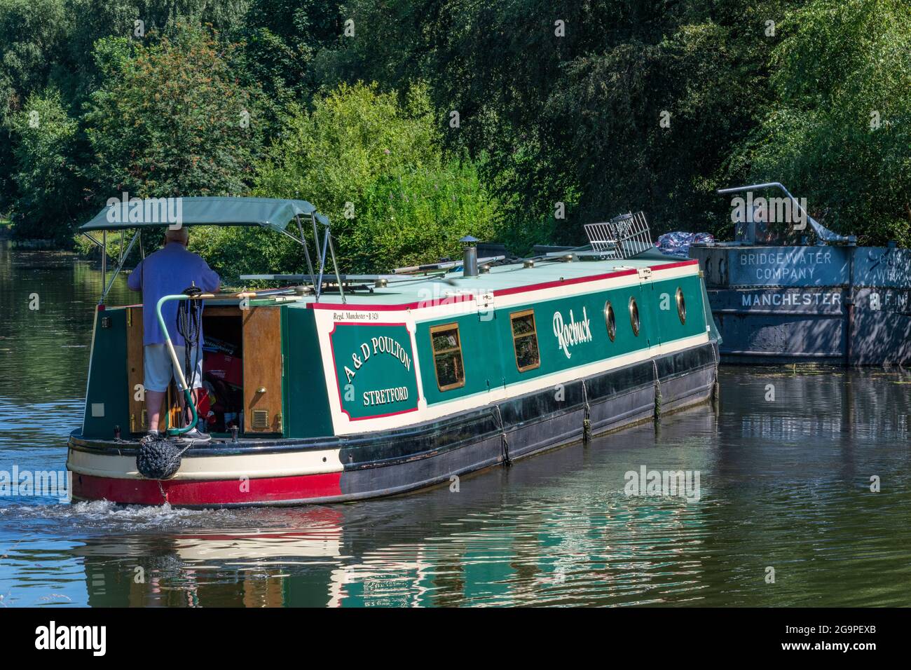 Mann, der am Steuer eines traditionellen Schmalboots oder Barges auf dem bridgewater-Kanal im Verkauf, Greater manchester, großbritannien, steuert Stockfoto