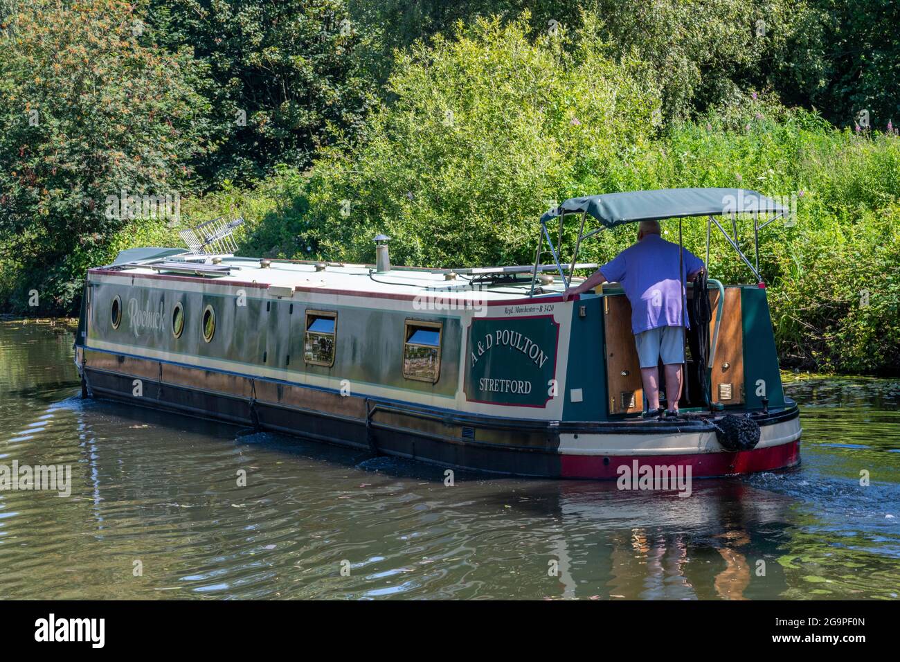 Mann, der am Steuer eines traditionellen Schmalboots oder Barges auf dem bridgewater-Kanal im Verkauf, Greater manchester, großbritannien, steuert Stockfoto