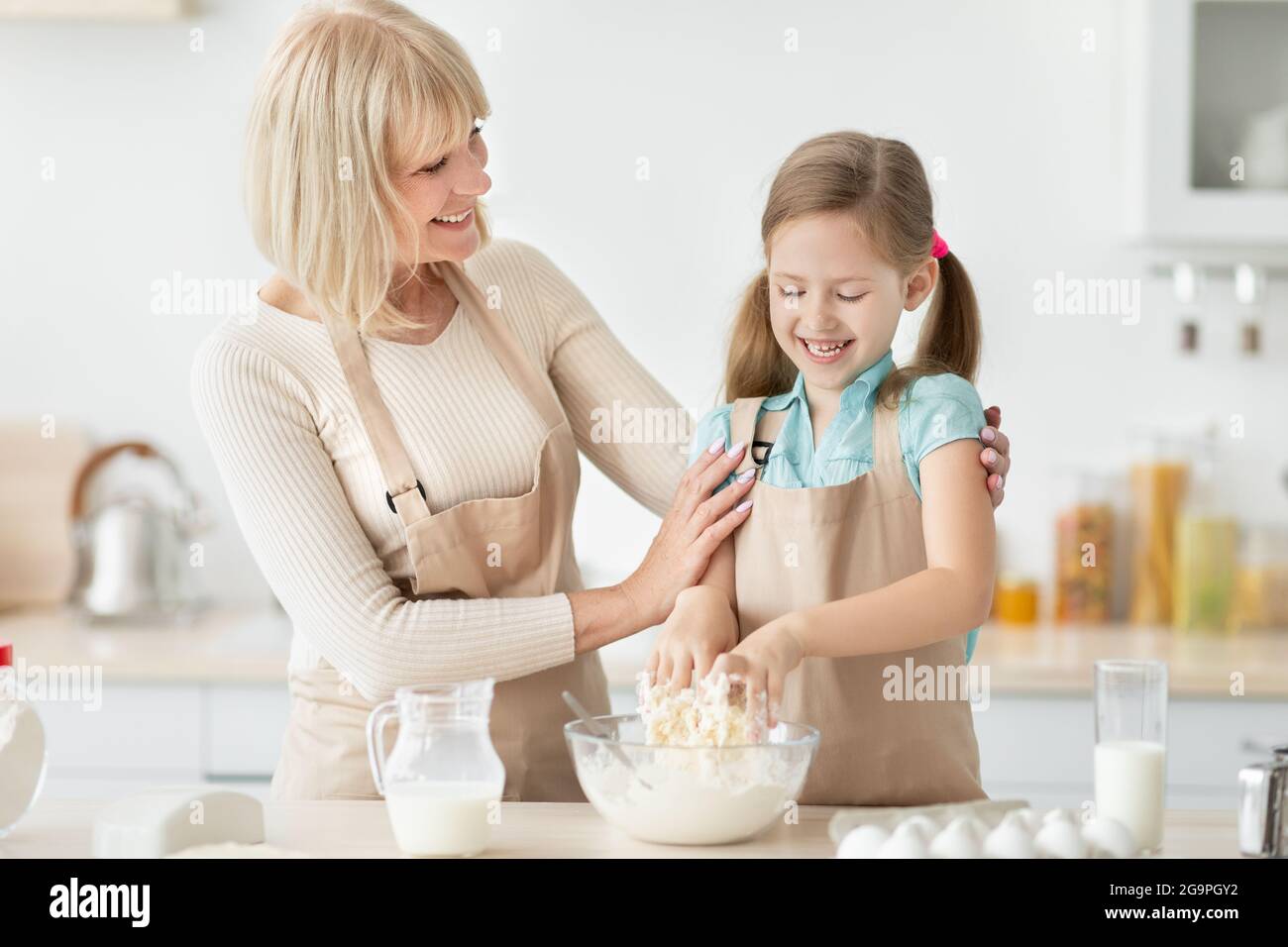 Glückliche ältere Frau und ihre Enkelin, die Teig zubereitet Stockfoto