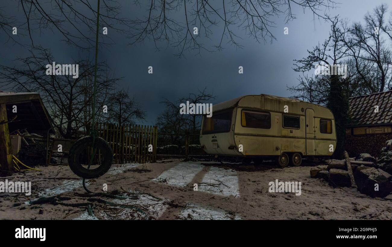 Alter Campinganhänger, der nachts auf einem Bauernhof im Winter steht, Deutschland Stockfoto