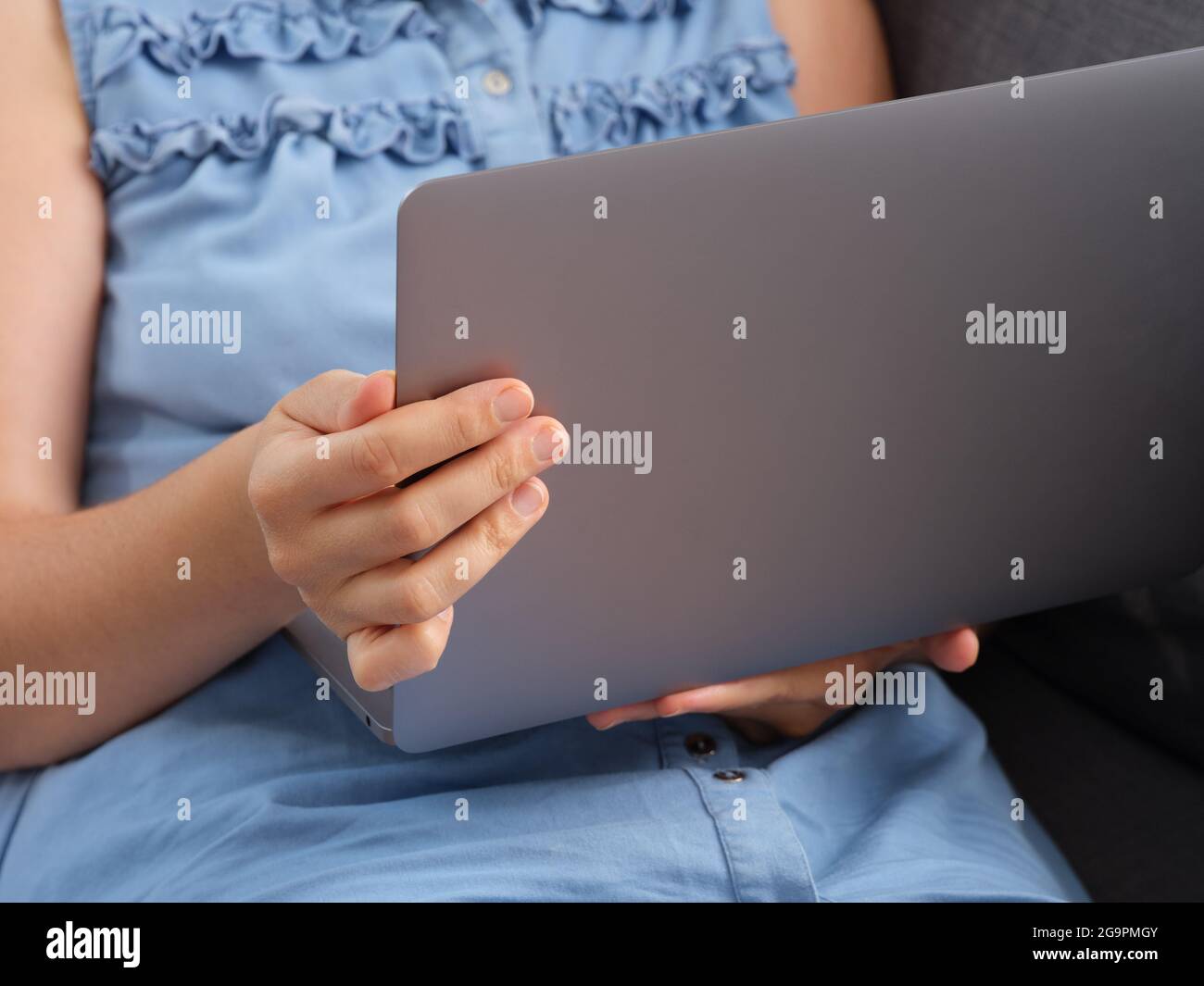 Eine Frau, die sich ein Video auf einem Laptop ansieht, während sie auf einer Couch sitzt. Nahaufnahme. Stockfoto