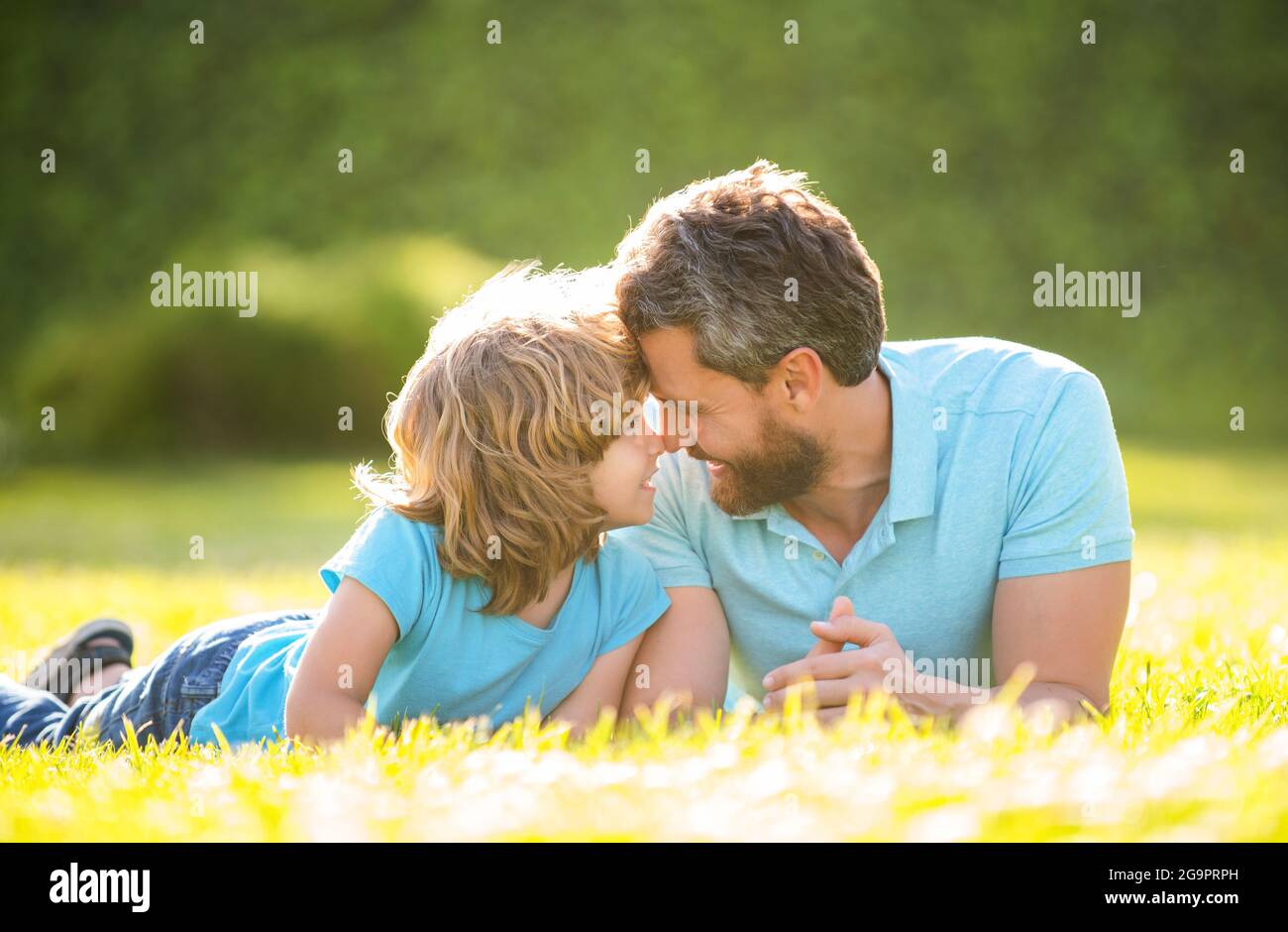 Eltern entspannen mit kleinen Jungen auf Gras. Papa mit Kind am Sommertag. Elternschaft und Vaterschaft Stockfoto