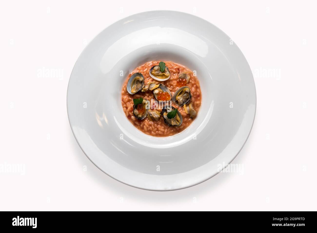 Gourmet-Risotto mit Venusmuscheln und rotem Kaviar in Platte isoliert auf weiß in der Draufsicht, flach gelegt Stockfoto