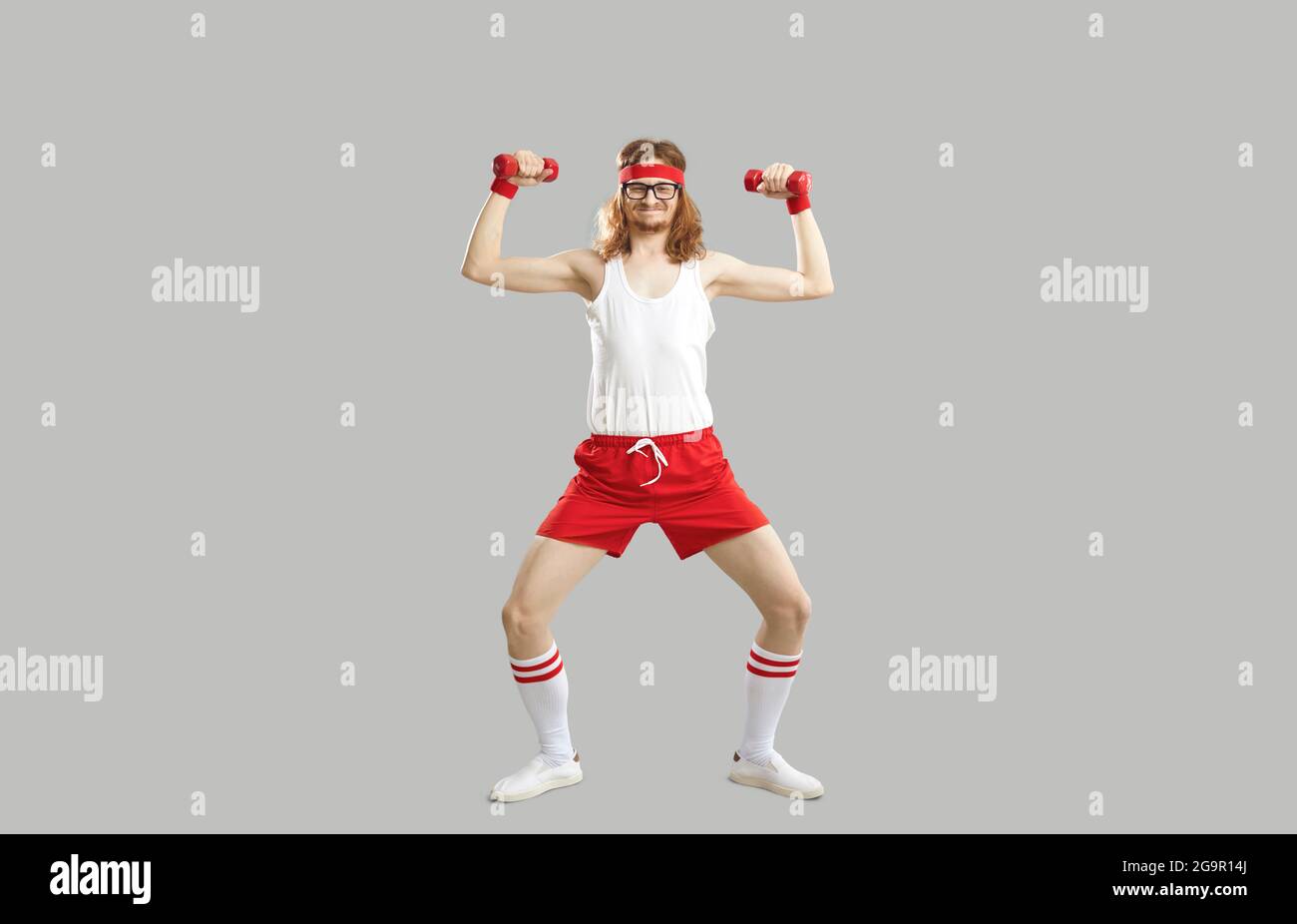 Lustige dünne Athlet macht Fitness-Übung mit Kurzhanteln isoliert auf grauem Hintergrund Stockfoto