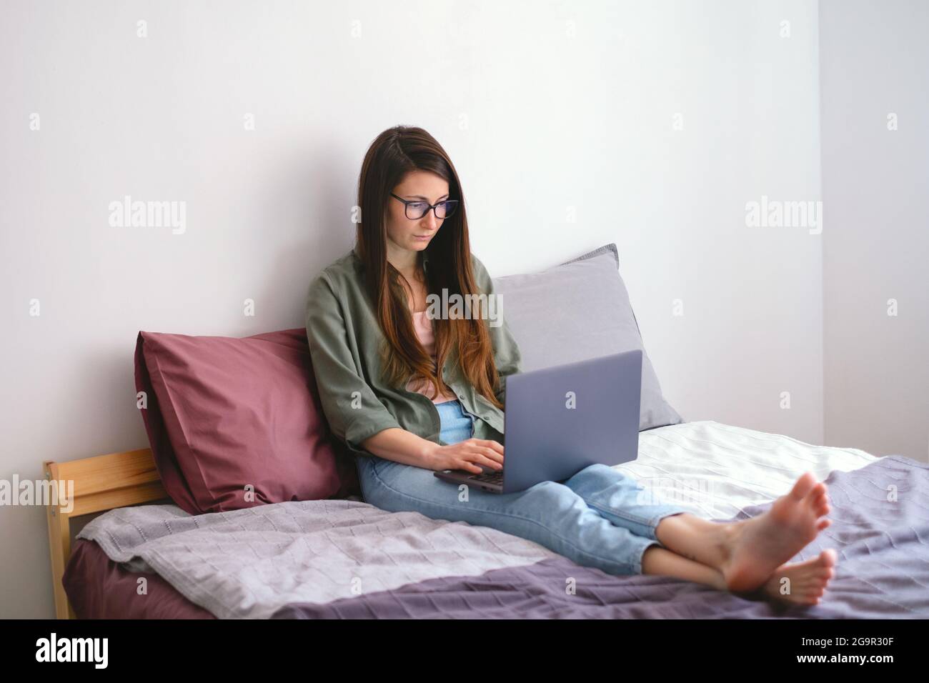 Junge freiberufliche Mitarbeiterin, die mit Laptop und Smartphone arbeitet. Remote-Job. Slow-Life-Konzept. Moderner Lifestyle. Stockfoto