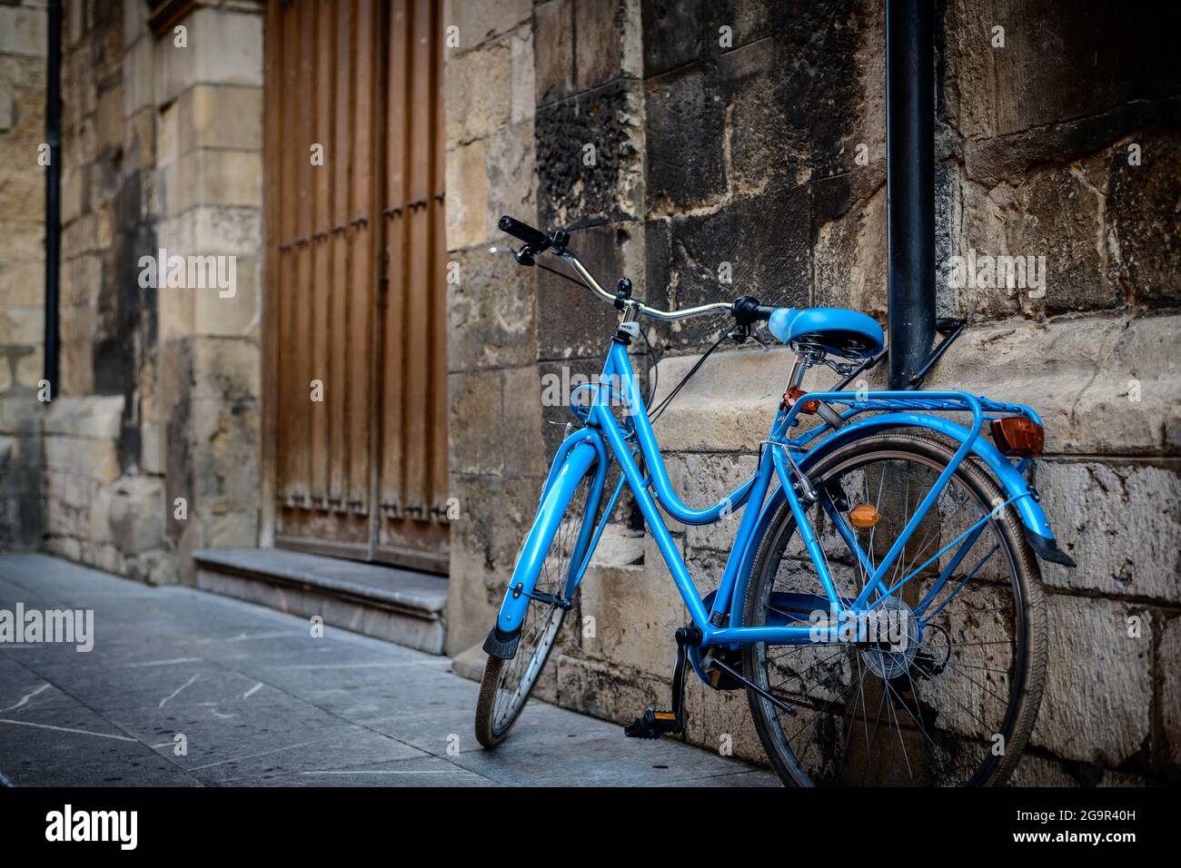 Blaues Fahrrad, das an der Wand einer alten Kirche angelehnt ist Stockfoto