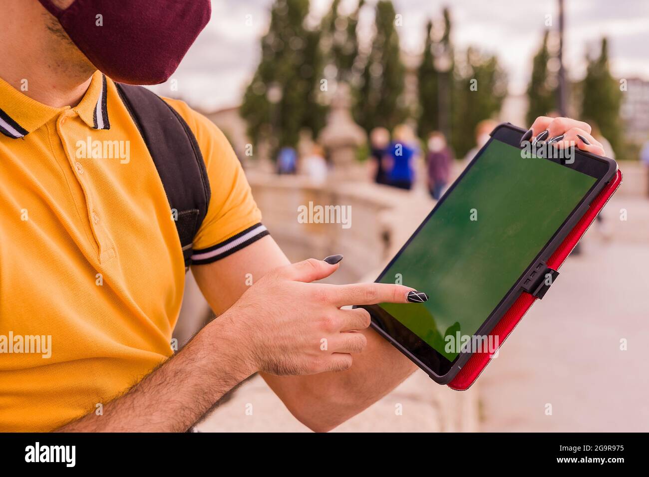 Lateinischer junger Mann verwendet ein digitales Tablet. Soziale Distanz bei einer neuen normalen Pandemie. Touchscreen mit Chroma-Taste Stockfoto