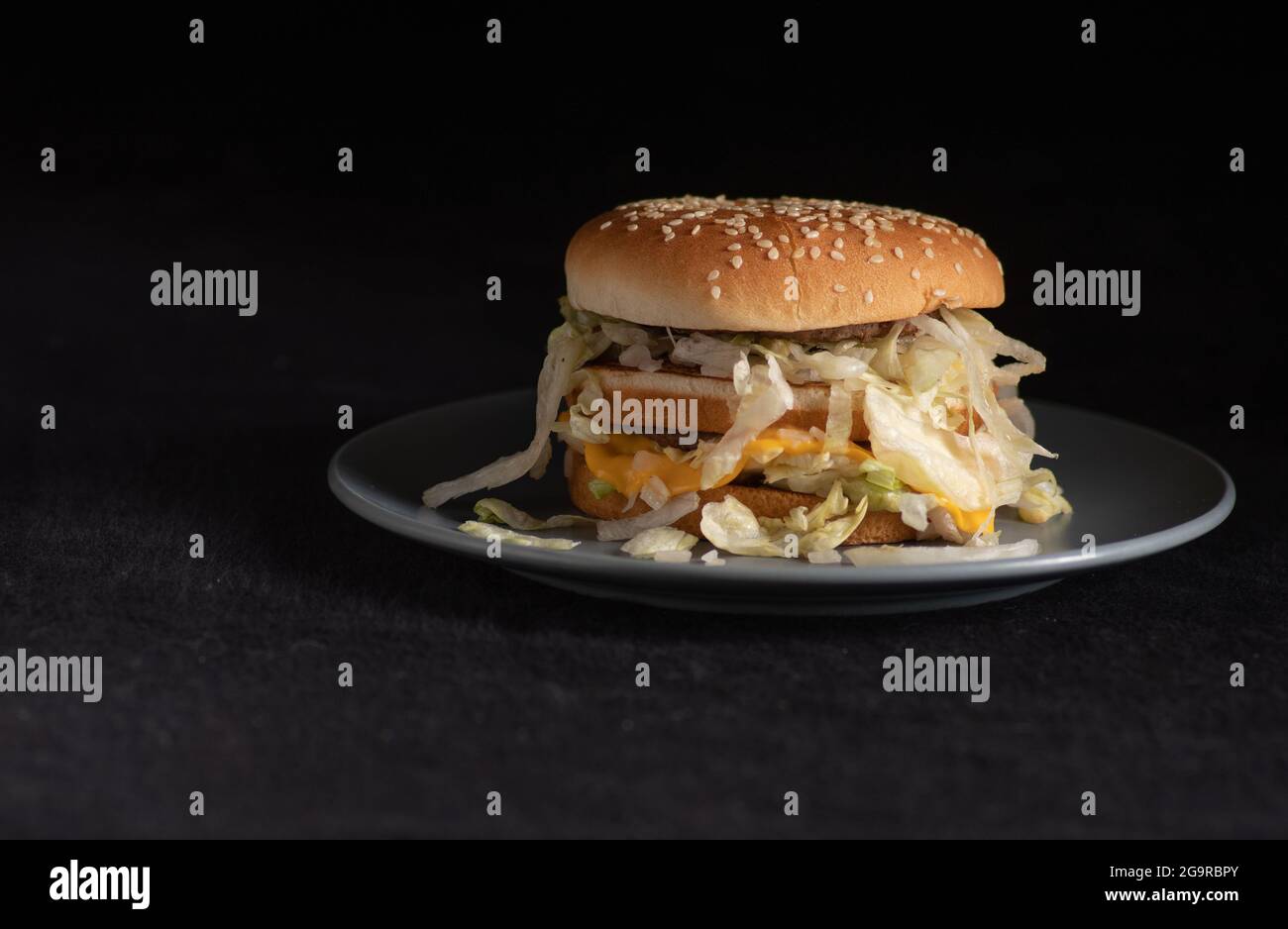 McDonalds Big Mac Hamburger auf einer grauen Untertasse auf dunklem Hintergrund überzogen Stockfoto