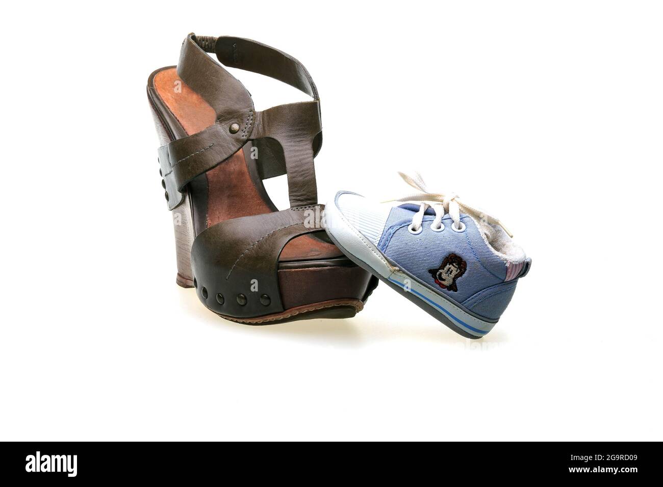 Eine braune Ledersandale für Frauen mit Korksohlen und ein blauer Sneaker für Kinder. Schuhe isoliert auf weißem Hintergrund. Stockfoto