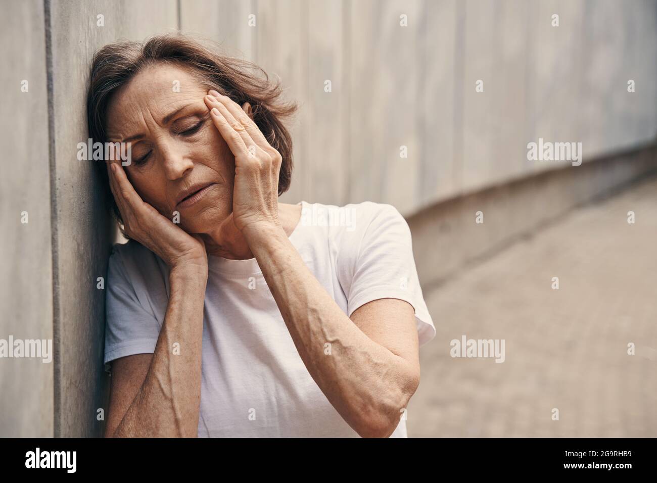 Ältere aktive Frau, die Schmerzen in Tempeln empfinden kann Stockfoto