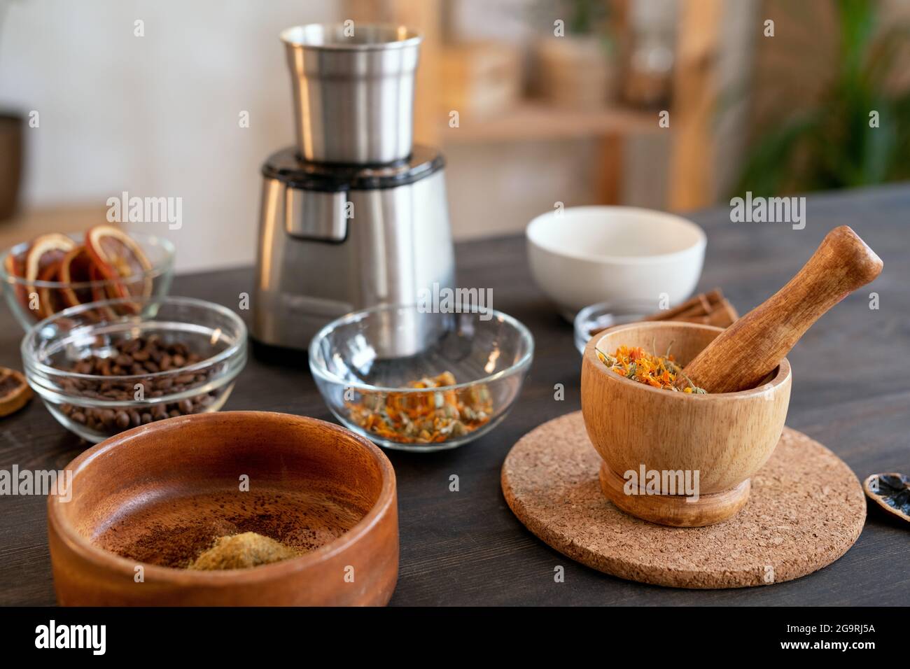 Gruppe von Schalen in verschiedenen Größen mit ätherischen Ölen, Kaffeebohnen, trockenen Blumen und anderen Zutaten für die Herstellung von Naturkosmetikprodukten Stockfoto