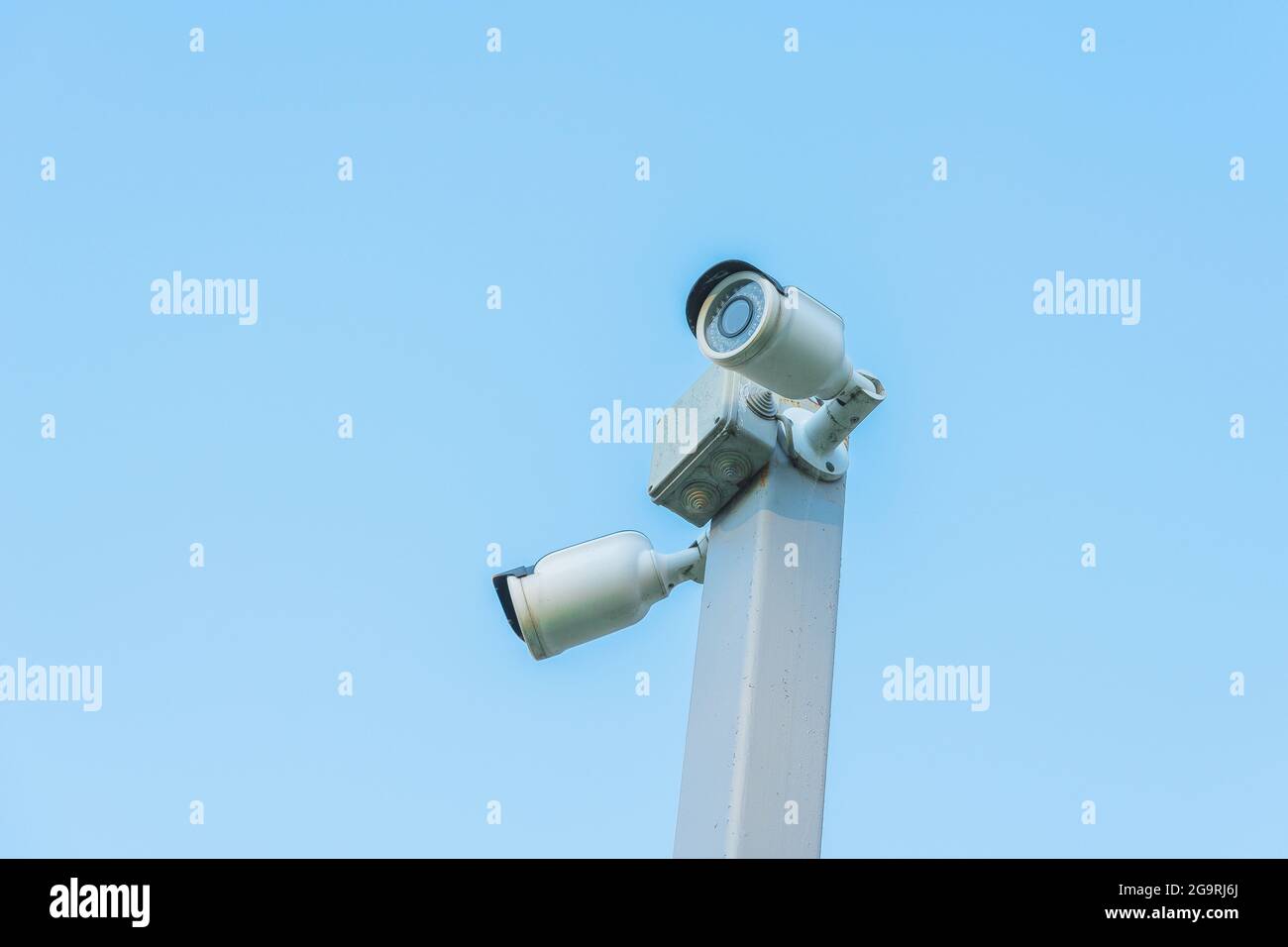 Alte Überwachungskameras auf dem grauen Pol mit blauem Himmel auf dem Hintergrund Stockfoto