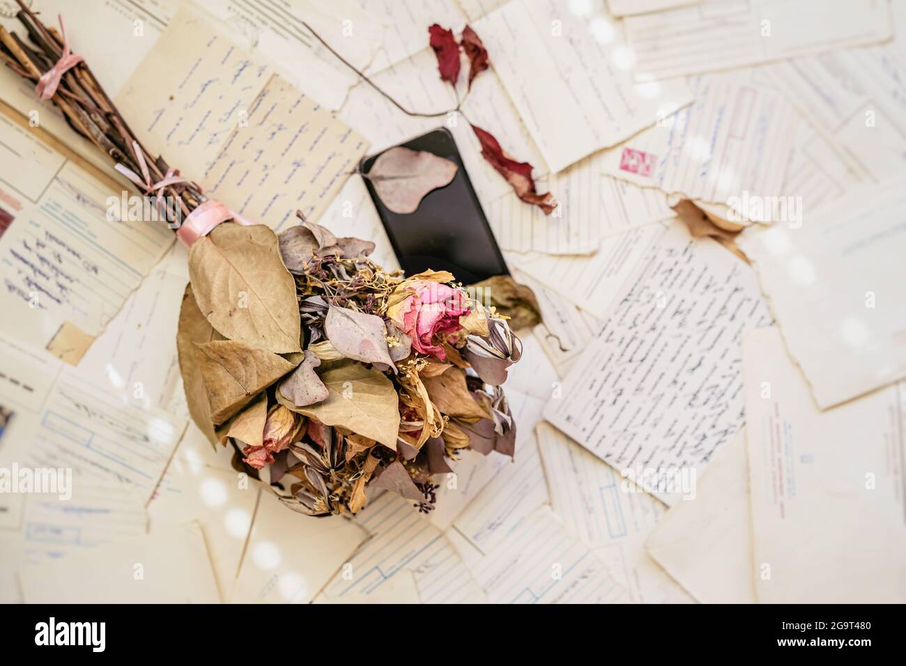 Alte Briefe, stilles altes Handy, getrockneter Blumenstrauß, Draufsicht. Konzept von Nostalgie, Erinnerungen und Einsamkeit Stockfoto