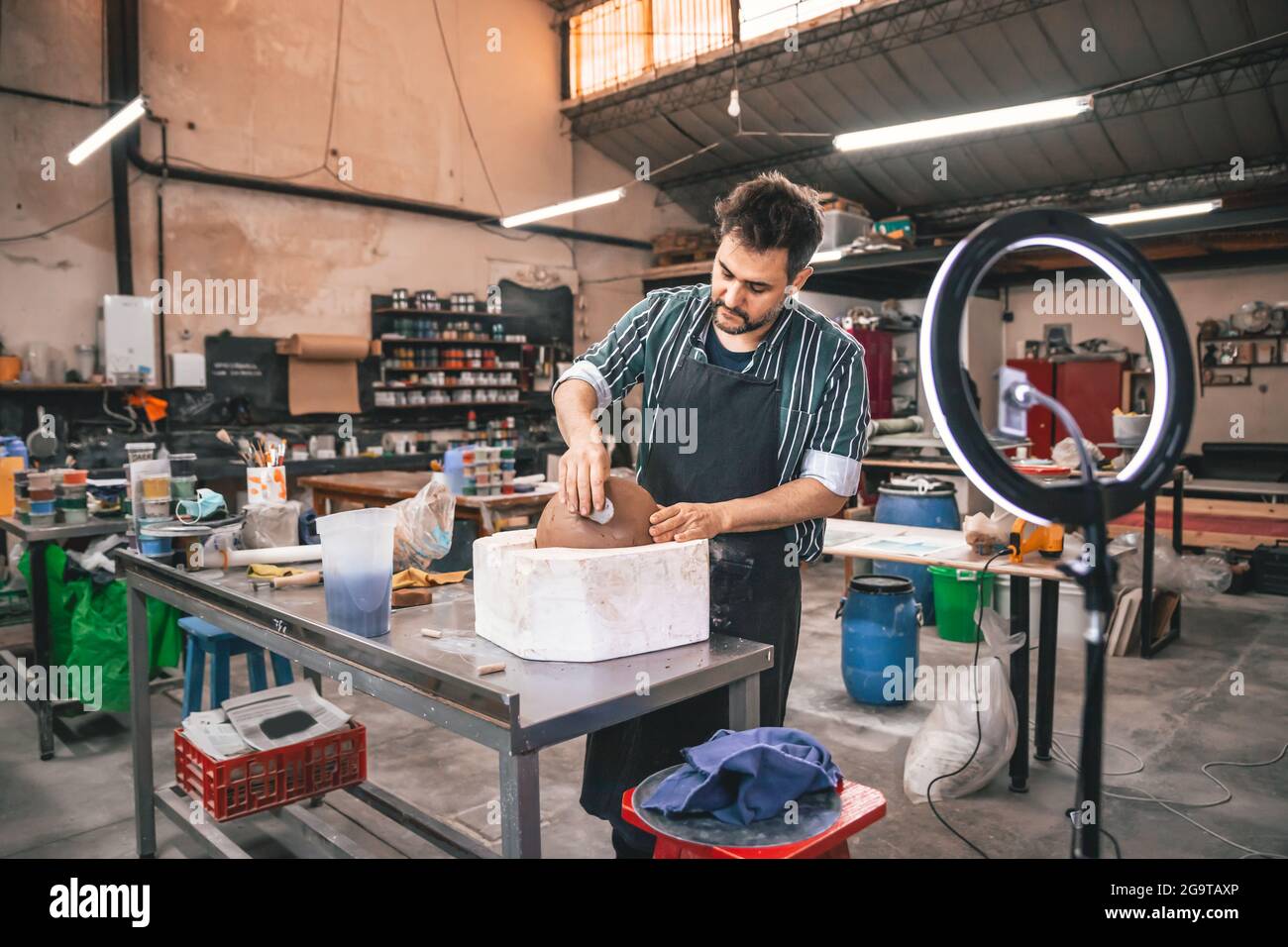 Erwachsener hispanischer Mann, der in einer Werkstatt einen Tontopf auf einem Tisch macht Stockfoto