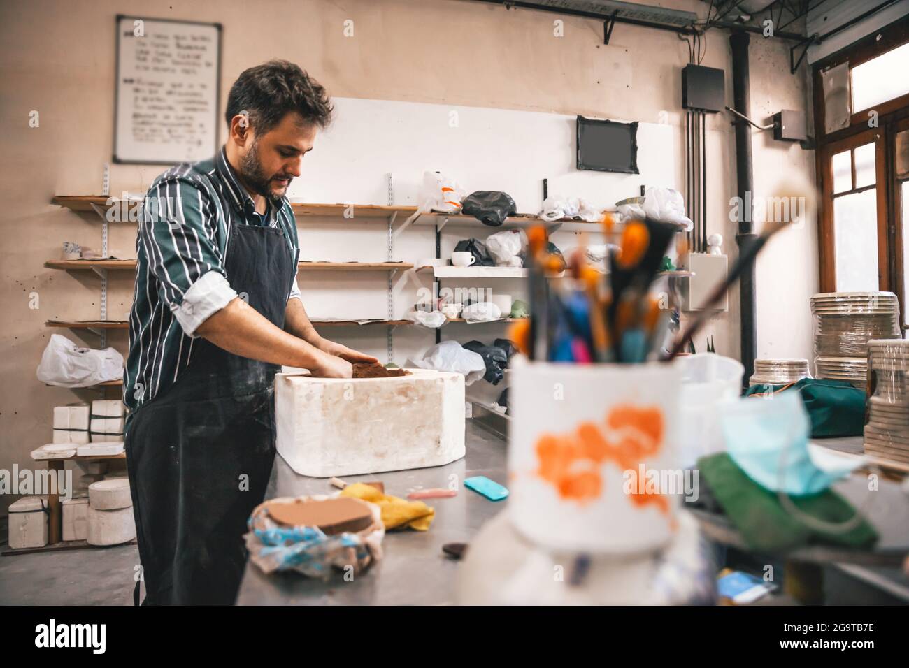 Erwachsener hispanischer Mann, der in einer Werkstatt einen Tontopf auf einem Tisch macht Stockfoto