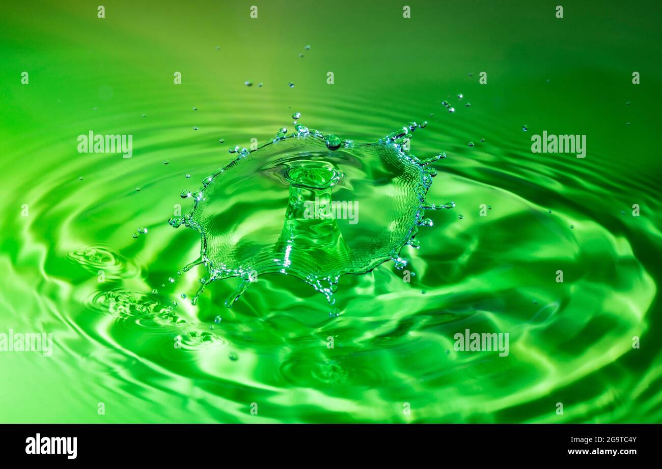 Kollision mit einem grünen Wassertropfen auf einer nahtlosen Oberfläche Stockfoto